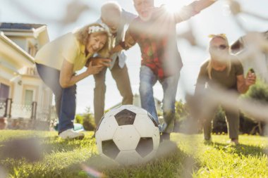 Bir grup aktif son sınıf öğrencisi arka bahçedeki çimlerde futbol oynayarak eğleniyor güneşli bir yaz gününün tadını çıkarıyor ve gol attıktan sonra kutlama yapıyorlar.