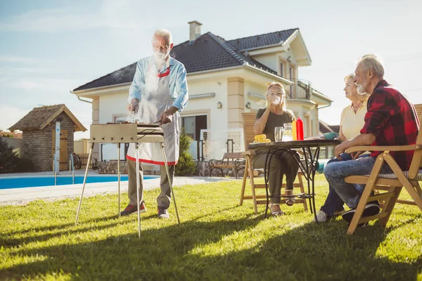 上了年纪的邻居们在户外度过一个阳光灿烂的夏天 在游泳池边举行一个后院烧烤派对 玩得很开心 — 图库照片