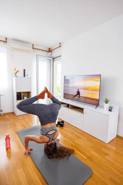 活跃的年轻女子穿着运动服在家里做网上瑜伽课 — 图库照片