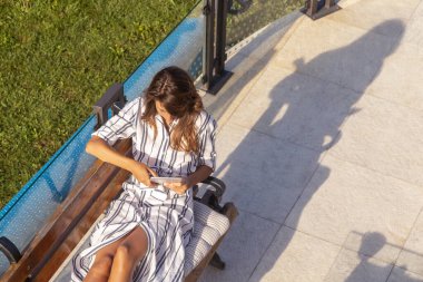 Evin arka bahçesindeki terasta dinlenen, dışarıda kahvaltı ederken kitap okuyan güzel bir kadının yüksek açılı görüntüsü.