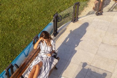 Arka bahçede rahatlayan, tablet bilgisayar kullanarak internette sörf yapan güzel bir kadının yüksek açılı görüntüsü.