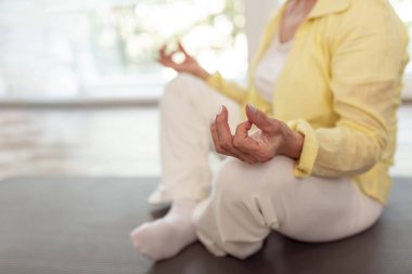 Aktif kıdemli kadının evde meditasyon eğitimi almasının ayrıntıları; yoga yapan yaşlı kadın - sağlıklı yaşam tarzı kavramı