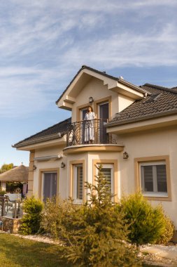 Yeni bir ev aldıktan sonra mutlu mesut yeni evinin balkonunda duran güzel genç bir kadın.