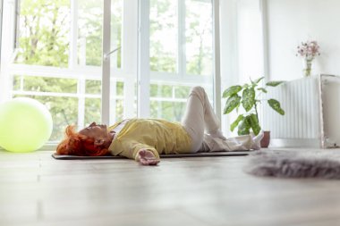Aktif kıdemli kadın yoga eğitimi alıyor ve evde dinleniyor, boş zamanlarının tadını çıkarıyor - yaşlıların sağlıklı ve aktif yaşam tarzı kavramı.