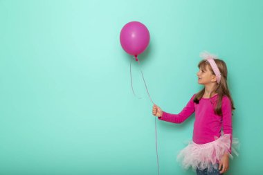 Doğum gününü kutlayan küçük güzel bir kızın portresi. Elinde pembe bir balon var. Arka planda izole edilmiş.