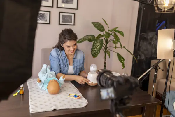 作为产前在线课程的一部分 女博客员录制了关于家用电器中婴儿奶瓶加热的视频 — 图库照片
