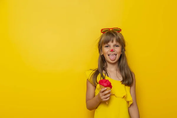 黄色の背景に隔離されたコーンでアイスクリームを食べながら楽しんでいる小さな女の子 — ストック写真