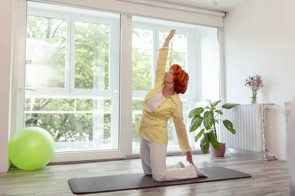 在家里练习瑜伽的老年妇女 老年人健康而积极的生活方式概念 — 图库照片