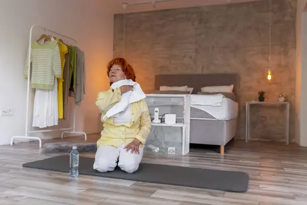 积极的老年妇女在做瑜伽训练后用毛巾擦汗 健康的生活方式概念 — 图库照片
