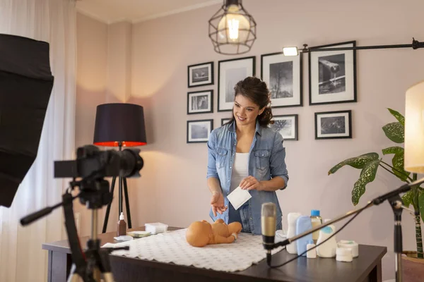 Female influencer recording educational newborn baby care videos about umbilical cord care and disinfection as part of online prenatal classes