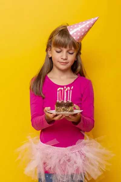 Mooi Klein Meisje Met Een Verjaardagshoed Een Verjaardagstaart Met Kaarsen — Stockfoto