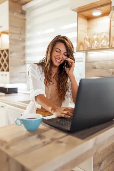 自宅からリモートで作業中に電話会話をする女性 ラップトップコンピュータを使用して電話で話す女性のWeb開発者 — ストック写真