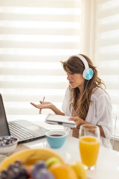 自宅からリモートで作業しながらオンラインミーティングを持つヘッドセットを着用している女性 — ストック写真