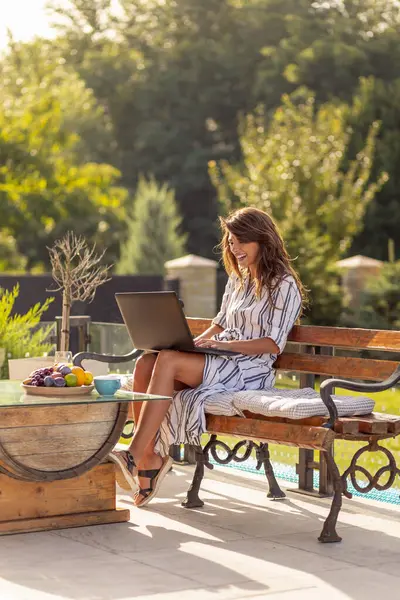 ラップトップコンピュータで働く女性フリーランサー コーヒーを飲み 屋外で晴れた夏の日を楽しんでいます — ストック写真