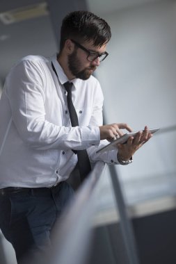 Başarılı bir işadamı bir ofis binasında elinde bir tablet bilgisayarla toplantıya hazırlanıyor.