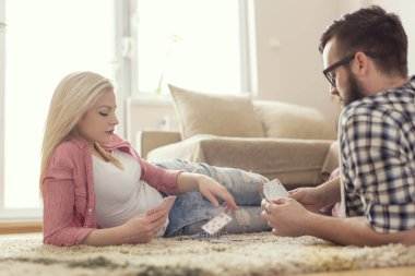 Genç ve güzel bir çift halının üzerinde uzanıyor, kart oynuyor ve günün tadını çıkarıyor. Cama yansıyan mercek, kıza odaklan.