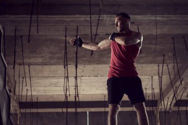 Genç atletik bir adam terk edilmiş bir binada çalışıyor, dövüş sanatları yapıyor.