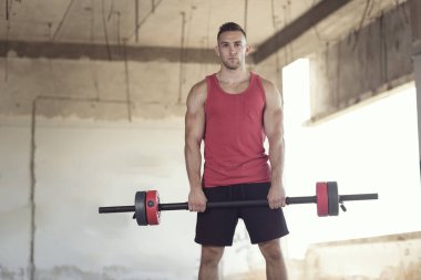 Elinde halter tutan genç bir sporcu halter antrenmanına hazırlanıyor.