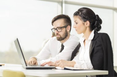 Bir ofiste bir dizüstü bilgisayar üzerinde çalışan iki iş arkadaşları