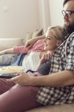 Genç çift evlerinde dinleniyor, kanepede uzanıyor, film izliyor ve patlamış mısır yiyor. Kıza odaklan.