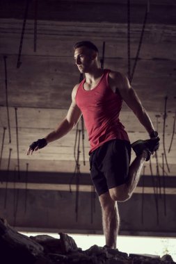 Genç sporcu, terk edilmiş bir binada antrenmandan önce ısınıyor.