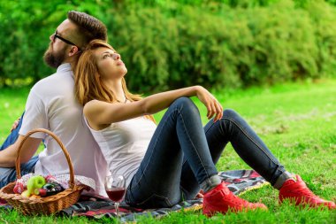 Piknik battaniyesinde oturan çift, düşünceli ve huzurun ve doğanın tadını çıkarıyor.