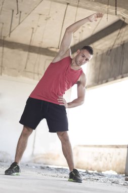 Atletik yapılı adam antrenmandan önce ısınma egzersizleri yapıyor.