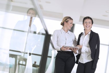 İki iş arkadaşı kahve molasında modern ofis koridorunda duruyor.