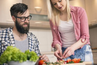 Aşık bir çift sebze keser ve birlikte yemek hazırlar.