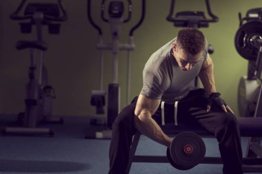 Spor salonunda çalışan, halter kaldıran ve halterleri kaldıran genç, kaslı bir sporcu.