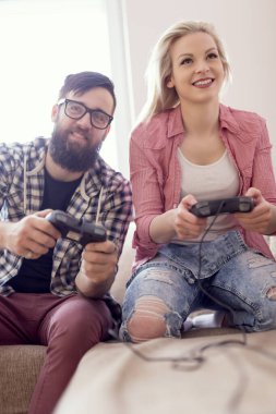 Birbirine aşık çiftler boş zamanlarında pencerenin yanındaki kanepede oturup video oyunları oynayıp eğleniyorlar. Cama yansıyan mercek, kadına odaklan.