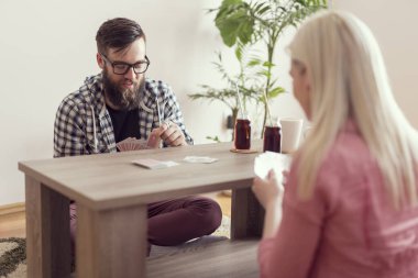 Genç aşık çift masanın yanında oturuyor, iskambil oynuyor, meyve suyu içiyor ve eğleniyorlar.. 
