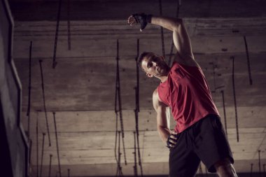 Kaslı, atletik yapılı, spor yapmadan önce harabe bir binada uzanan genç bir adam.