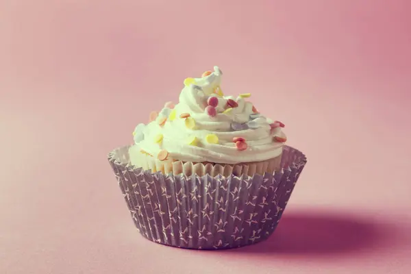 クリームとピンクの背景に単離された上にクリームで美しく装飾されたカップケーキ — ストック写真