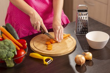 Taze sebze salatası yapmak için mutfak bıçağıyla taze havuç kesen kadın elleri.