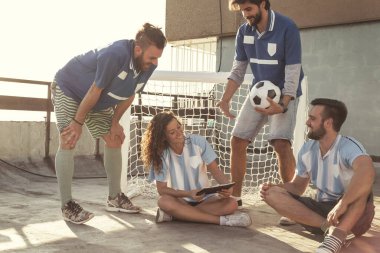 Bir grup genç arkadaş bir binanın terasında futbol oynarken eğleniyorlar, mola veriyorlar, oyun stratejisini planlıyorlar ve tahtaya çiziyorlar.