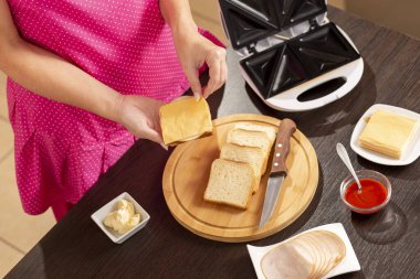 Bir sandviçe peynir dilimi ekleyen kadın eli kahvaltıda sandviç yapan kadın.