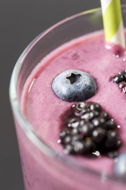 Kırsal bir masaya yerleştirilmiş bir bardaktaki yabanmersinli smoothie 'nin üst görüntüsü.