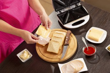 Bir sandviçe peynir dilimi ekleyen kadın eli kahvaltıda sandviç yapan kadın.