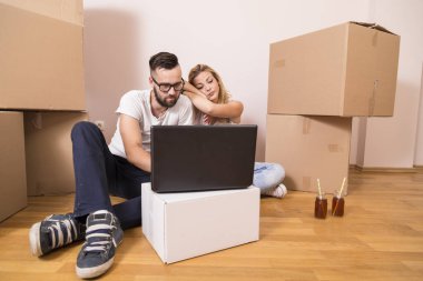 Birbirine aşık genç bir çift yeni evlerinin zemininde oturmuş yeniden dekore etmeyi ve meyve suyu içmeyi planlıyorlar.