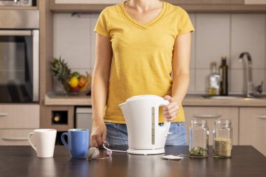 Sabahları çay yapan kadın elinde kaynar su dolu bir çaydanlık tutuyor.