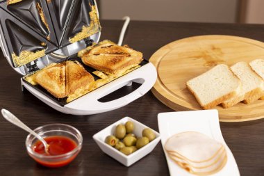 Sandviç makinesinde yenmeye hazır sıcak sandviçlerin ayrıntıları. Sandviçlere ve ekmek dilimlerine odaklan.