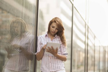 Ofis dışında tablet bilgisayarında çalışan genç bir iş kadını.