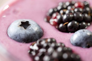 Kırsal bir masaya yerleştirilmiş bir bardaktaki yabanmersinli smoothie 'nin üst görüntüsü.