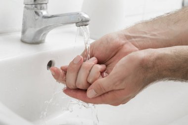 Lavaboda ellerini yıkayan bir adama yaklaş.