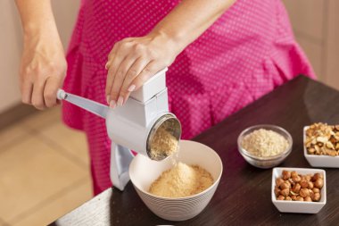 Bisküvi öğütme makinesinde bisküvi öğüten bir kadının yüksek açılı görüntüsü. Kılçıkları makineye iten ele odaklan