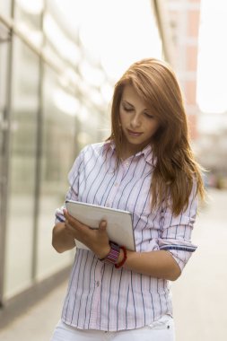 Ofis dışında tablet bilgisayarında çalışan genç bir iş kadını.