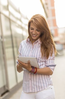 Ofis dışında tablet bilgisayarında çalışan genç bir iş kadını.