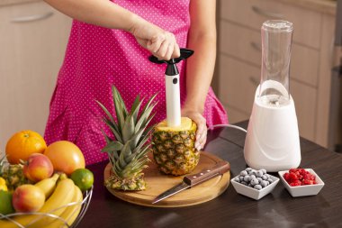 Ananas keskisiyle ananas soyan bir kadın taze, sağlıklı, çiğ meyve püresi yapıyor.