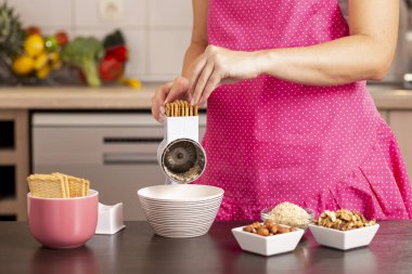 Bisküvi öğütücüsü kullanan, bisküvileri öğütme makinesine koyan bir kadın elinin ayrıntıları. Bisküvilere odaklan. 